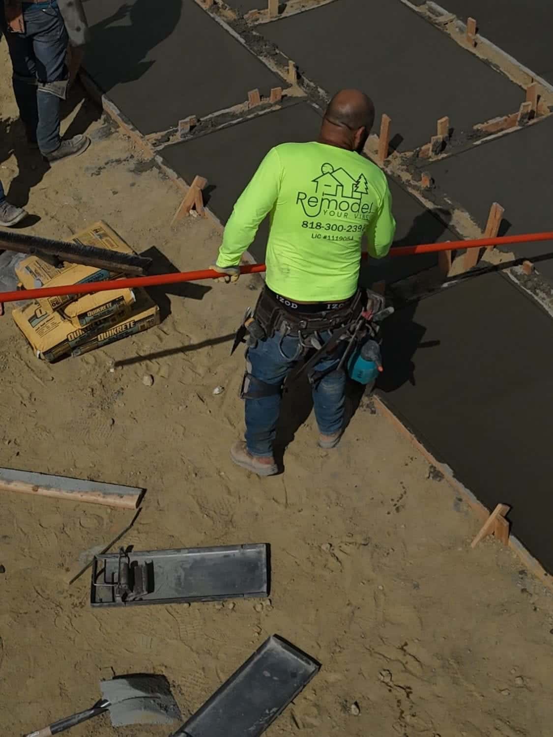 Crew member working a fresh concrete pour set in wood forms