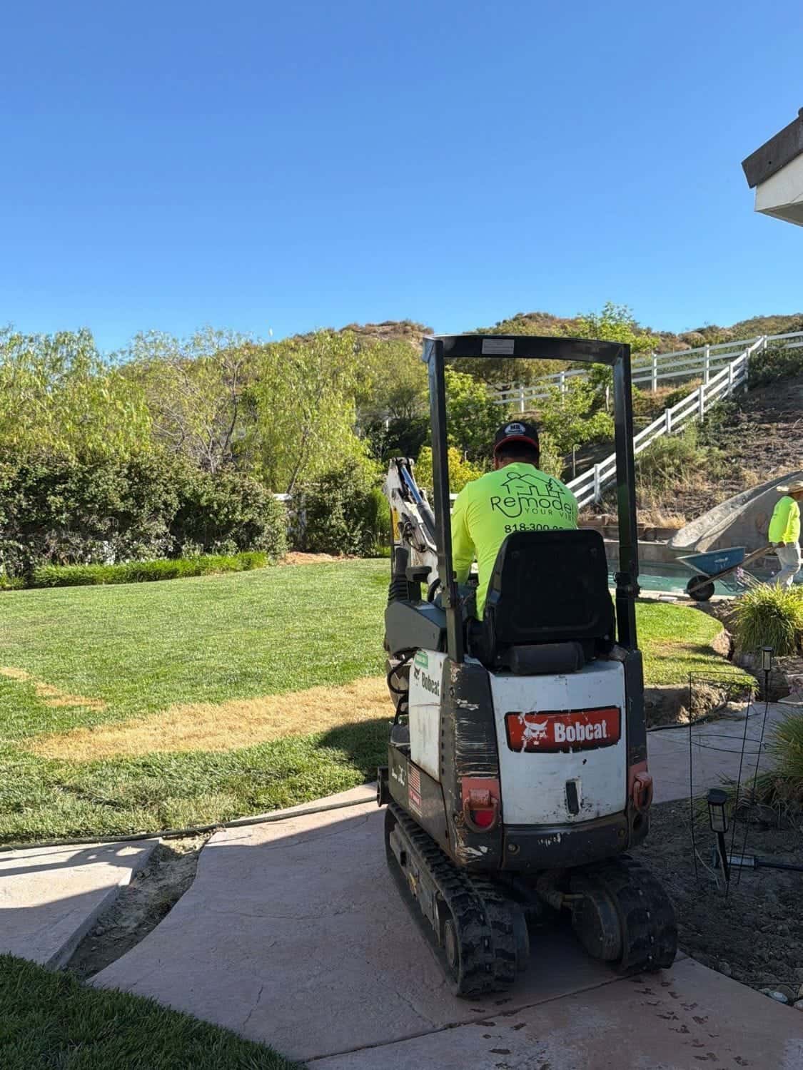 Mini excavator heading into a backyard to start work