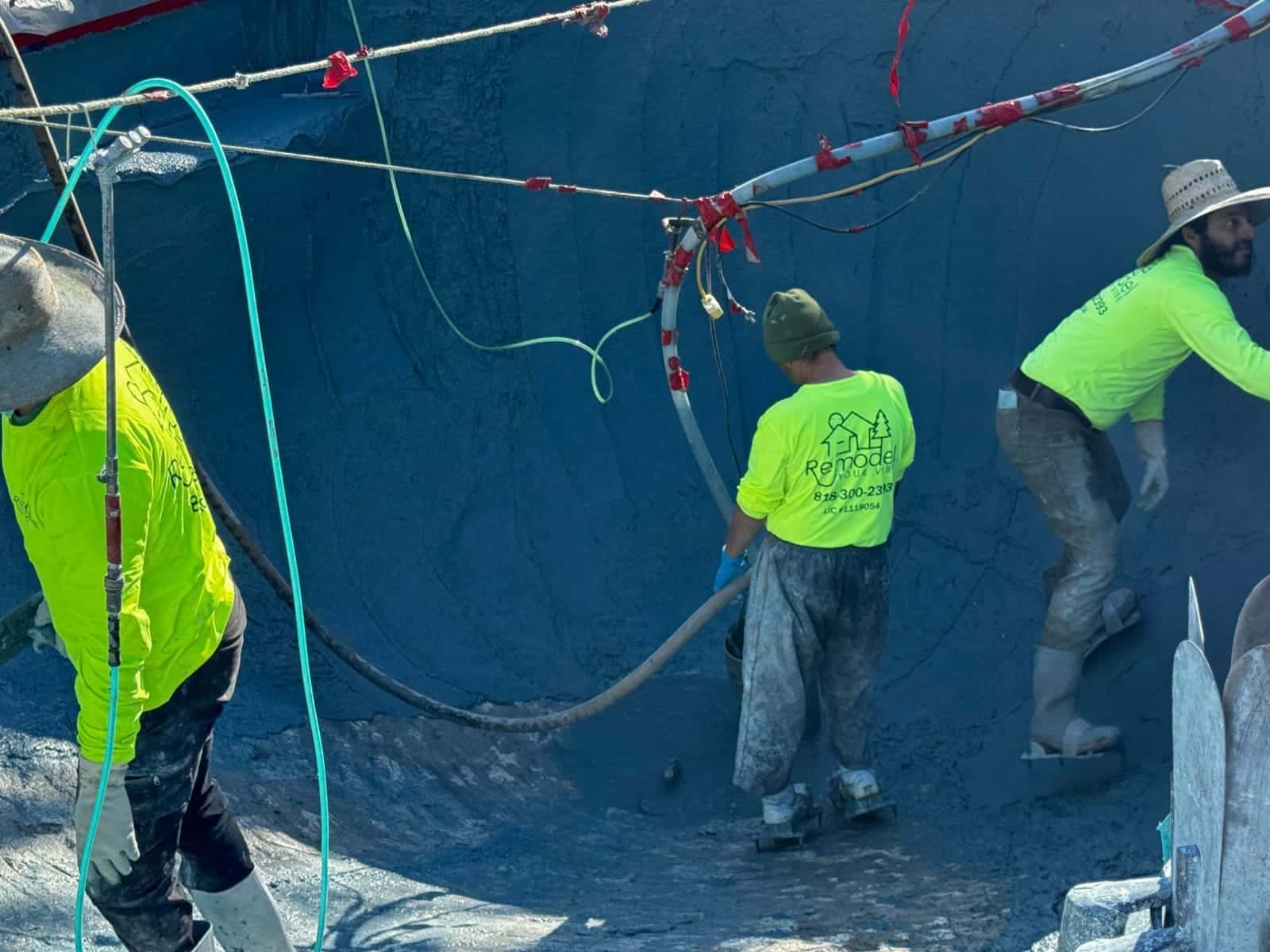 Crew running the plaster hose through a pool shell