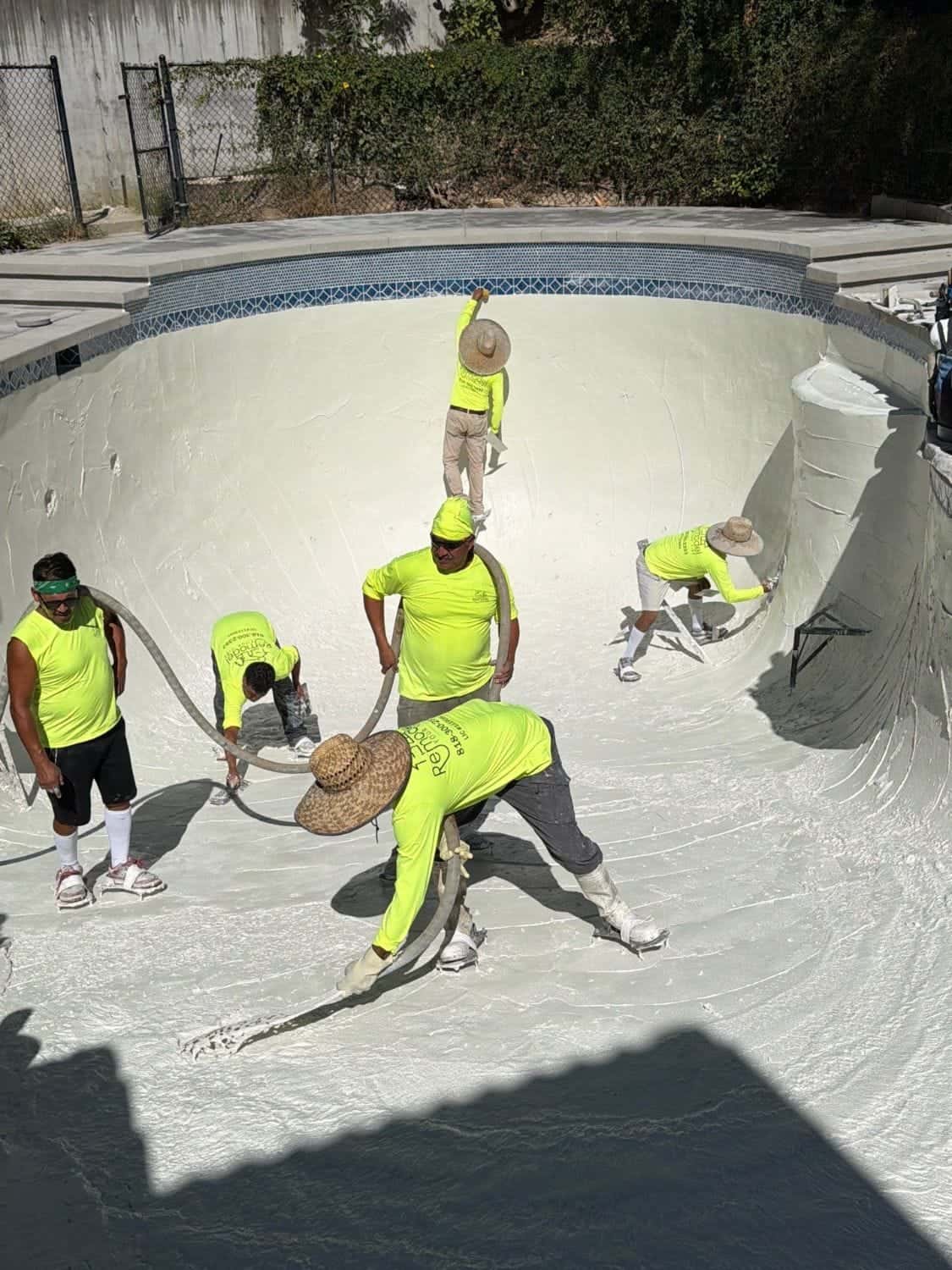 Our crew applying fresh white plaster across a pool floor and walls
