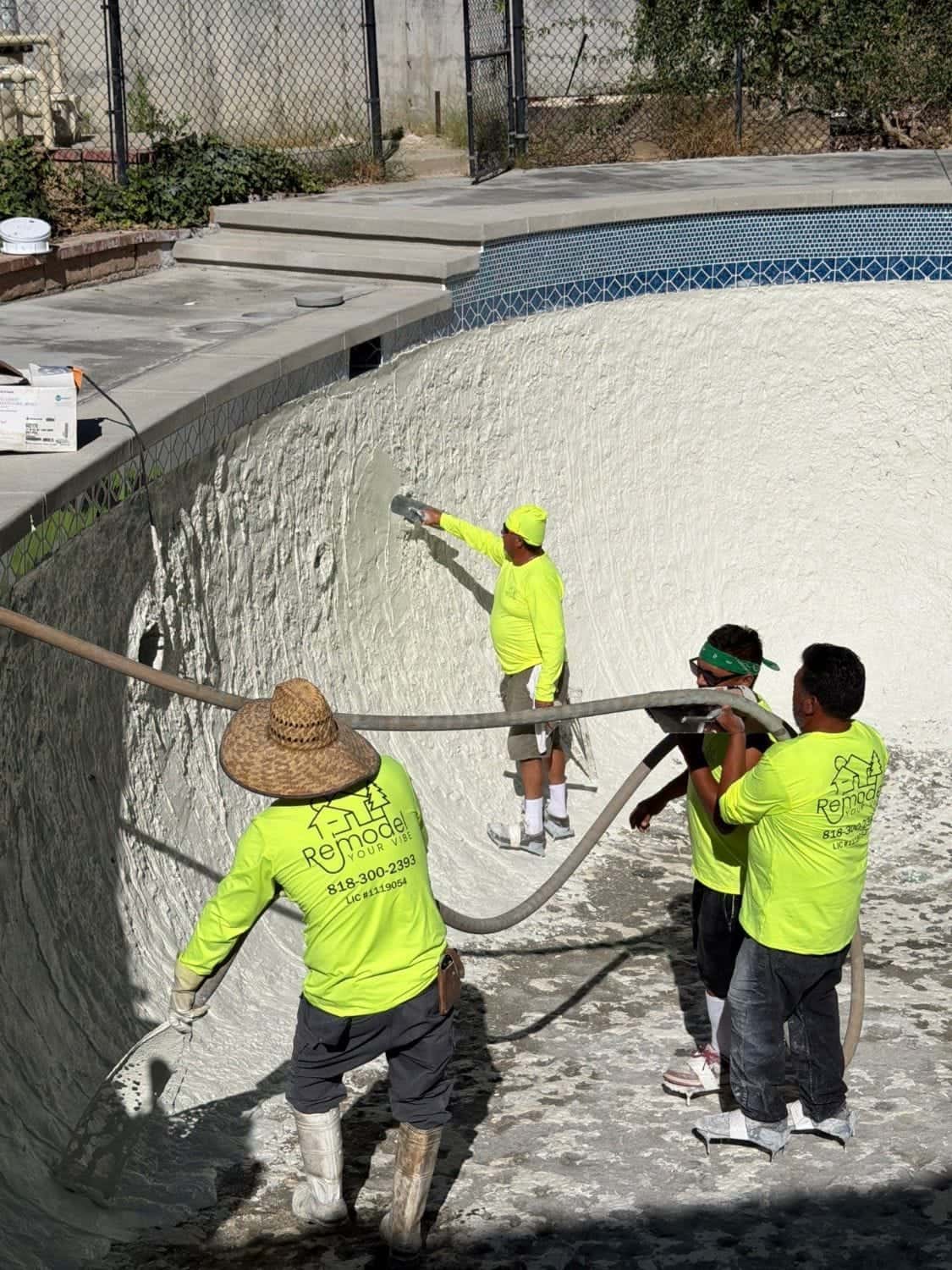 Crew guiding the plaster hose around a freeform pool