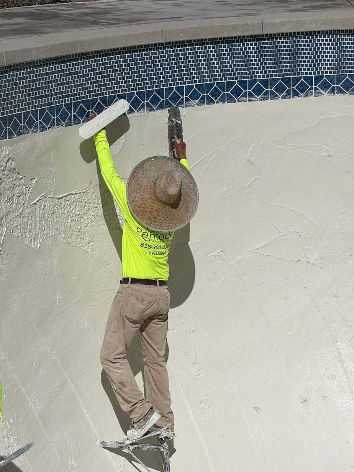Plasterer troweling a pool wall up to the tile line