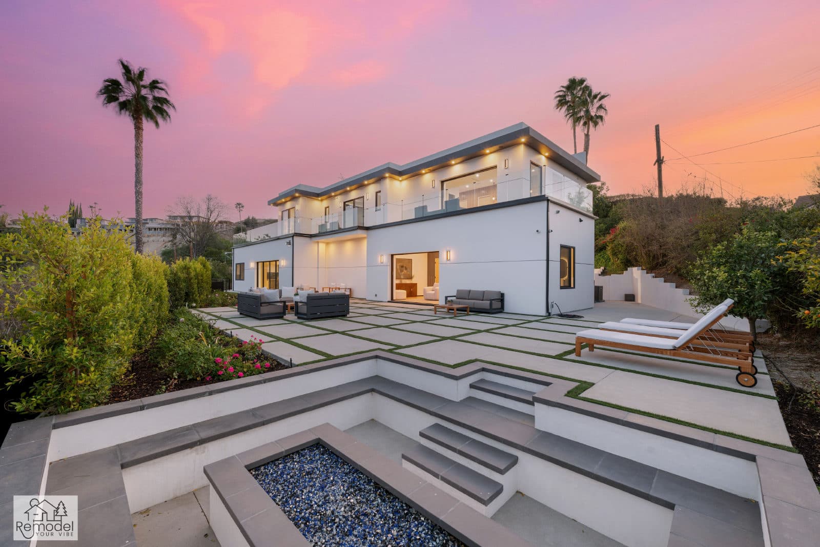 Sunken fire-pit lounge with built-in seating below a modern home at twilight