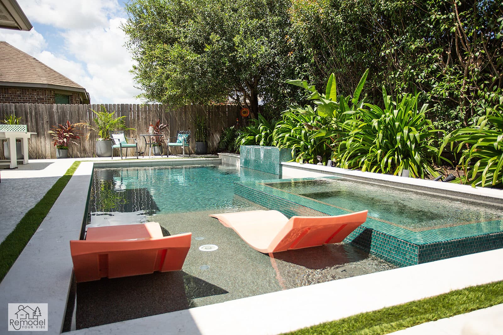 Pool with in-water loungers and a spa spillway framed by tropical planting